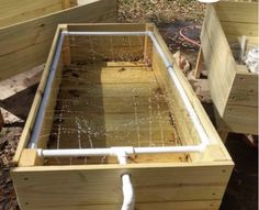 a wooden box with water coming out of it and some pipes in the back ground