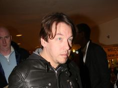 a man in a leather jacket is looking at the camera