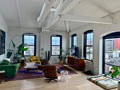 a living room filled with lots of furniture next to tall windows and potted plants