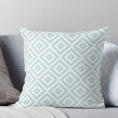 a blue and white pillow sitting on top of a gray couch next to two pillows