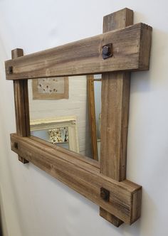 a mirror hanging on the side of a wall next to a wooden frame with hooks