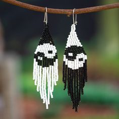 the beaded earrings are decorated with black and white beads, which hang from a tree branch