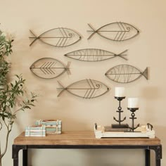 metal fish wall art hanging on the wall next to a table with candles and books