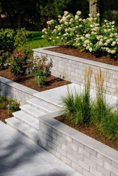 an outdoor garden with white brick walls and flowers in the foreground, surrounded by shrubbery