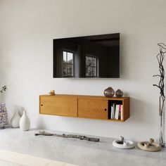 a tv mounted on the wall next to a shelf with vases and other items