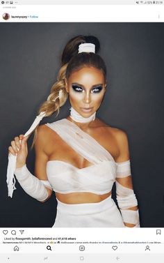 a woman in white is posing with her hair pulled up into a high pony tail