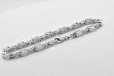 Here we have a beautiful lab created White Opal Sterling Silver tennis Bracelet. Opals feature cabochon oval cut in prong setting. Bracelet is about 5 carats of gemstone total weight. This bracelet was designed to allure and impress. It will be an excellent addition to a jewelry collection due to its unique design. The bracelet is made out of solid 925 Sterling Silver and 14k white gold overlay for that timeless and classic look. Brand new item, never worn. Other lengths available per especial r Oval Cabochon Bracelet In Fine Jewelry Style, Oval Cabochon Bracelets Fine Jewelry, Oval Cabochon Bracelet Fine Jewelry, Elegant Silver Oval Cabochon Gemstones, Fine Jewelry Cabochon Bracelets As Gift, Classic White Oval Link Jewelry, Elegant Oval Cabochon Gemstones, Elegant White Cabochon Gemstones, Classic Oval Sterling Silver Bracelet With 17 Jewels