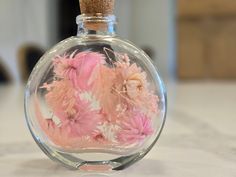 a glass bottle filled with pink flowers on top of a table