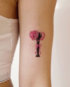 a woman's arm with a tattoo on it that has a pink rose in the shape of a heart