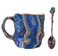 a blue mug with a spoon next to it on a white background and an object in the foreground