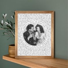 a wooden shelf with a framed photograph on top of it next to a potted plant