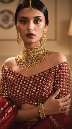 a woman wearing a gold and red bridal outfit