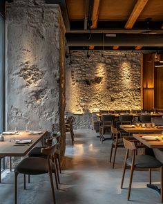 an empty restaurant with stone walls and wooden tables