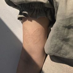 the back of a person's leg with a butterfly tattoo on their left arm