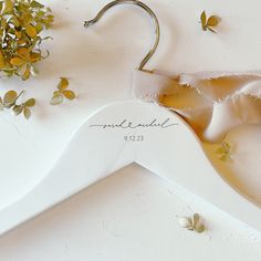 a wedding dress hanger with flowers on it next to a pair of scissors and some leaves