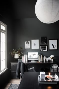 a room with black walls and pictures hanging on the wall, along with a desk