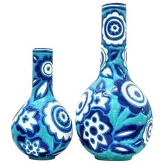 two blue vases sitting next to each other on a white surface with flowers painted on them