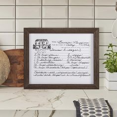 a kitchen counter with a framed recipe print on the wall next to a potted plant