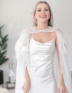 a woman in a white dress and feather cape