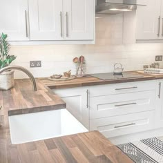 a kitchen with white cabinets and wood counter tops