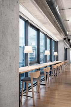 a long table with chairs and lamps next to large windows