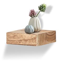 two ceramic flowers in a white vase on a wooden shelf