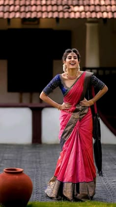 a woman in a red and black sari standing next to a potted plant