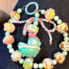 an assortment of colorful beads and charms on a black surface with a keychain