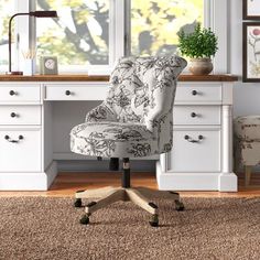 an office chair sitting in front of a desk with drawers and pictures on the wall