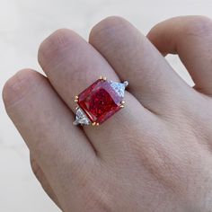 a woman's hand with a red and white diamond ring on top of it