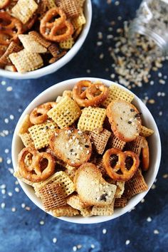 two bowls filled with cheetos and pretzels on top of a table