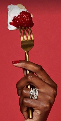 a woman's hand holding a fork with a piece of cake on top of it