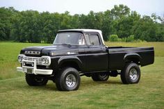 an old black pickup truck parked in a field