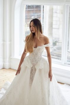 a woman in a white wedding dress is posing for the camera with her hands on her hips