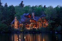 a large house sitting on top of a lake surrounded by trees and water at night