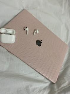 an apple laptop computer with ear buds attached to it's cover on a bed