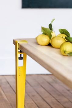 some lemons are sitting on a wooden table with a yellow pole in the foreground