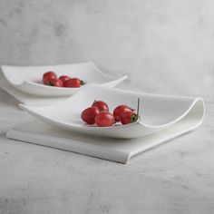 two white plates with tomatoes on them sitting on a counter top next to each other