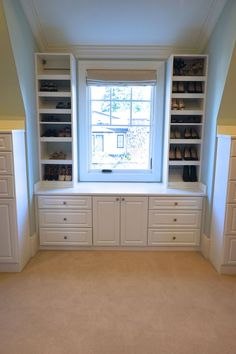 an empty room with built - in shelves and shoes on the windowsill, along with carpeted flooring