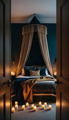 candles are lit on the floor in front of a bed with drapes and curtains