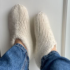 someone's feet wearing knitted slippers in front of a white door handle