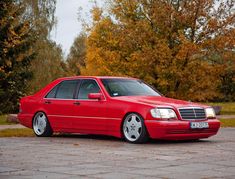 a red car parked in front of some trees