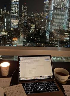 an open laptop computer sitting on top of a desk next to a cup of coffee