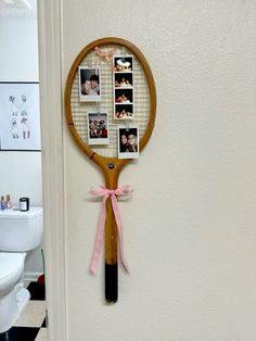 a tennis racket hanging on the wall with photos attached to it's side