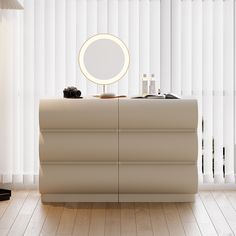 a white dresser with a round mirror on top