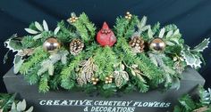 a christmas centerpiece with pine cones, evergreens and berries on it's side