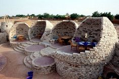 an outdoor dining area with stone walls and tables in the middle, surrounded by sand dunes