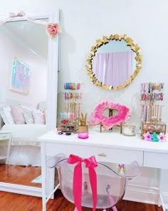 a white desk topped with a mirror and lots of pink accessories on top of it