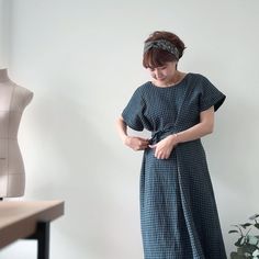 a woman standing in front of a mannequin wearing a dress and headband