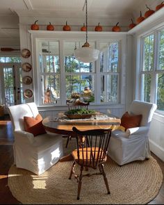 a dining room with chairs and a table in front of two large windows that look out onto the water